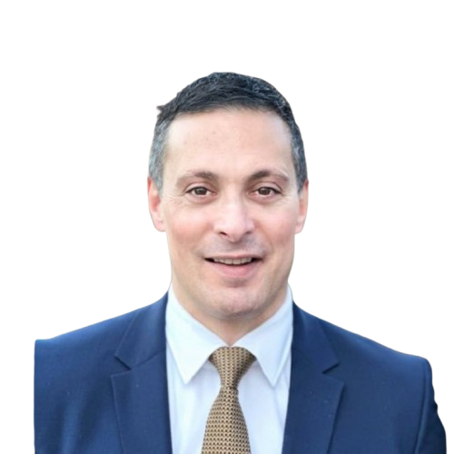 Man in a suit and tie smiling at the camera against a plain background.